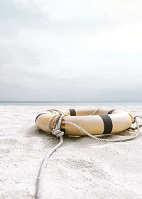 Photograph of lifebuoy on light sandy beach with ocean in the background-7