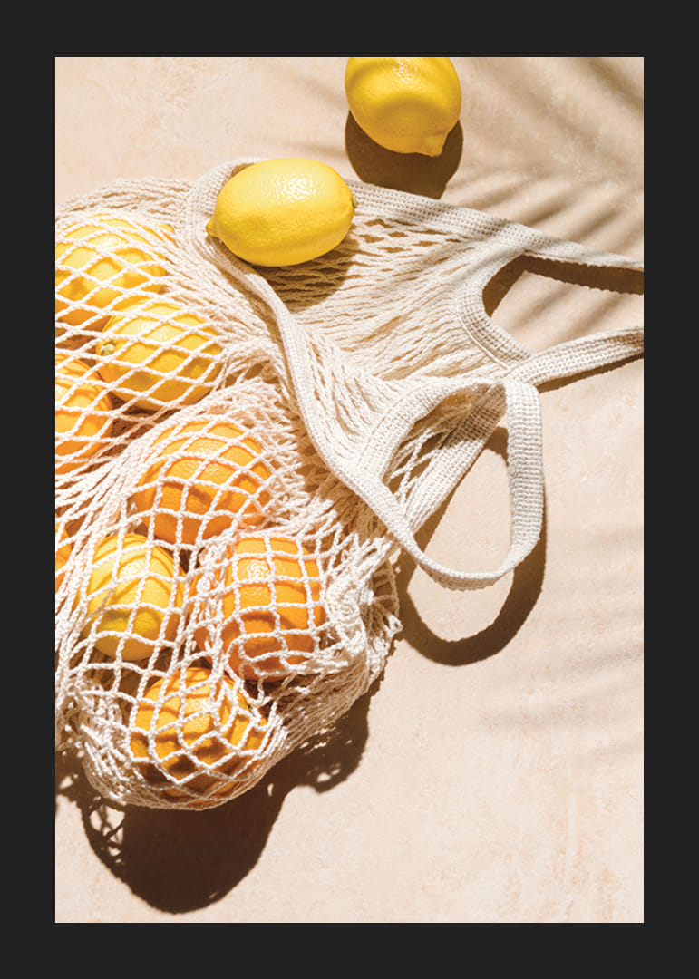 Fotografisk närbild av citroner i nätkasse på ljust underlag-12