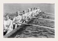 Schwarz-weiße Gruppe von Frauen rudert in einem langen Boot auf ruhigem Wasser-3