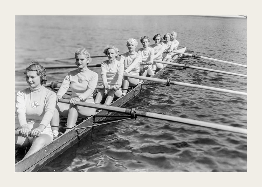 Schwarz-weiße Gruppe von Frauen rudert in einem langen Boot auf ruhigem Wasser-12