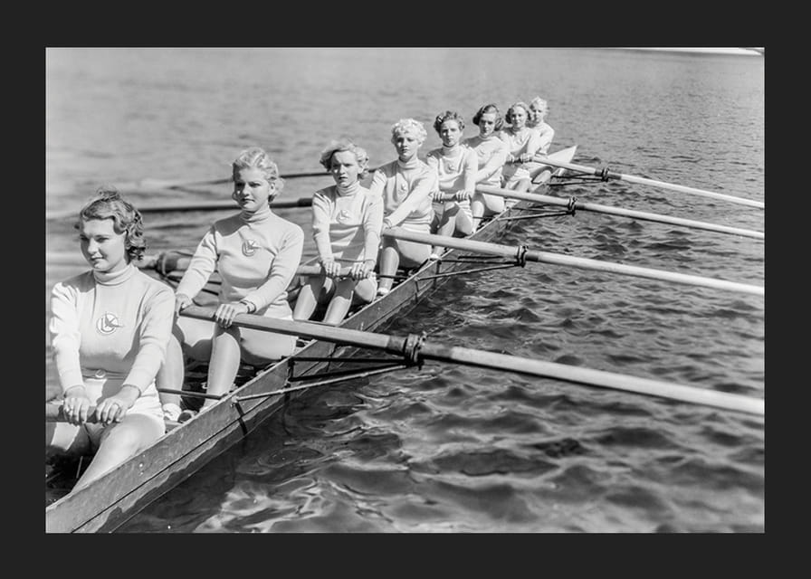 Schwarz-weiße Gruppe von Frauen rudert in einem langen Boot auf ruhigem Wasser-12