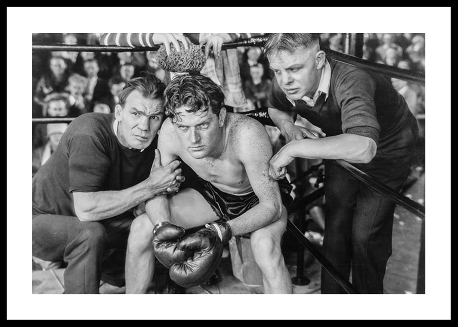 Black and white scene with boxer and two trainers in ring corner-12