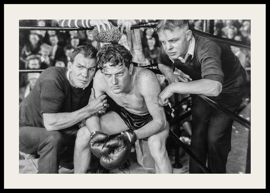 Black and white scene with boxer and two trainers in ring corner-12
