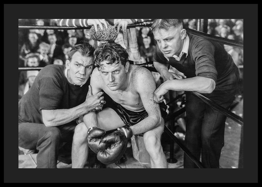 Black and white scene with boxer and two trainers in ring corner-12