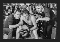 Black and white scene with boxer and two trainers in ring corner-5