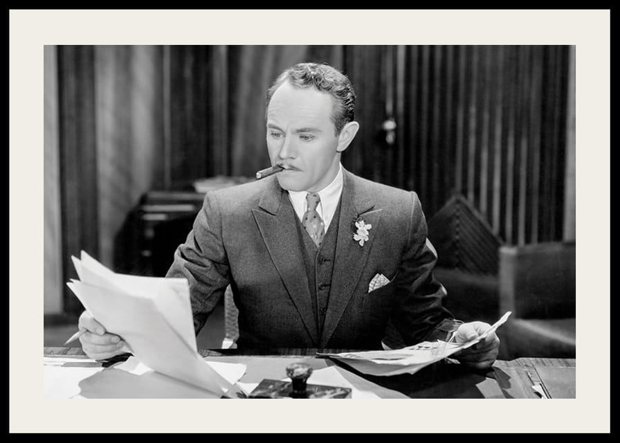 Svartvitt foto av man i kostym med cigarr vid skrivbord-12