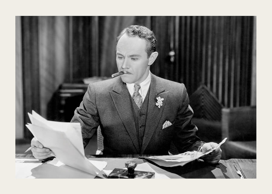 Svartvitt foto av man i kostym med cigarr vid skrivbord-12