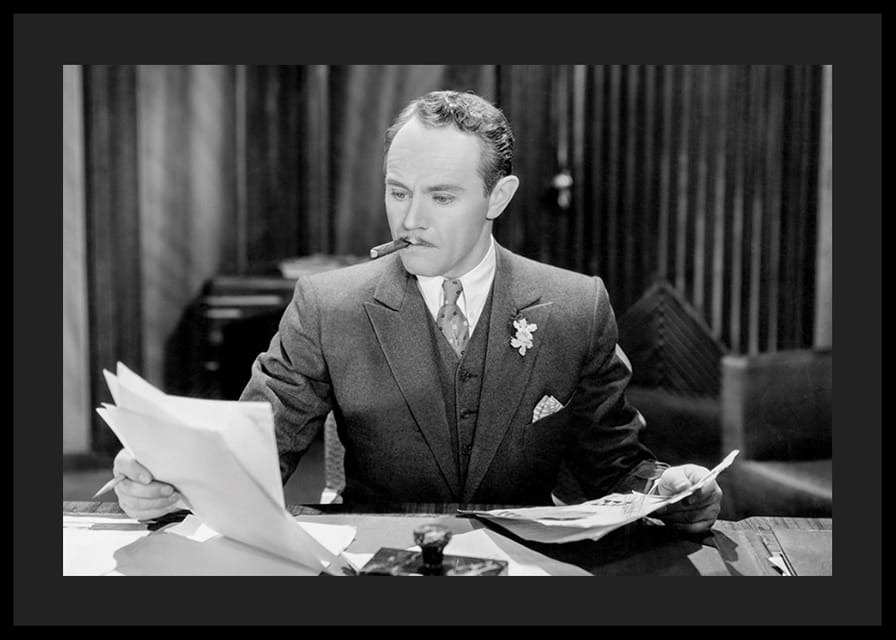 Svartvitt foto av man i kostym med cigarr vid skrivbord-12