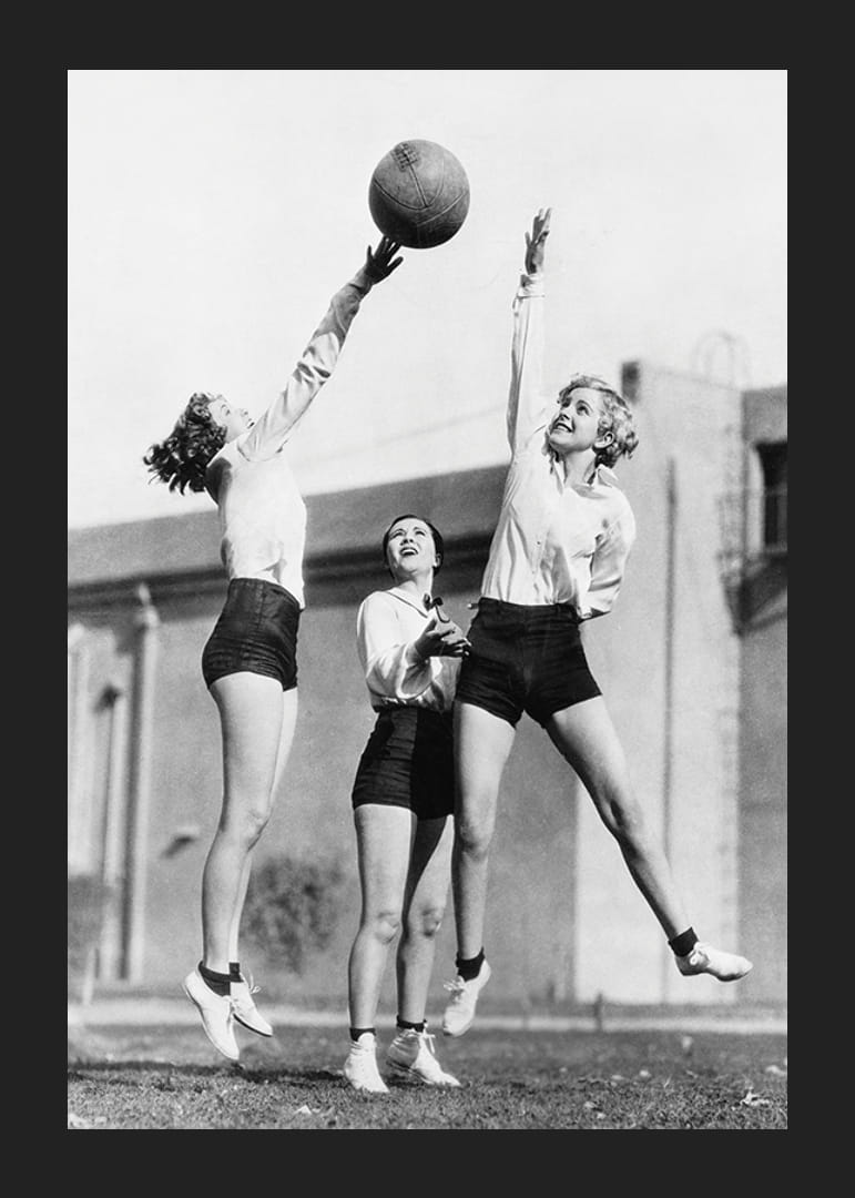Black and white photograph of three women playing basketball outdoors-12