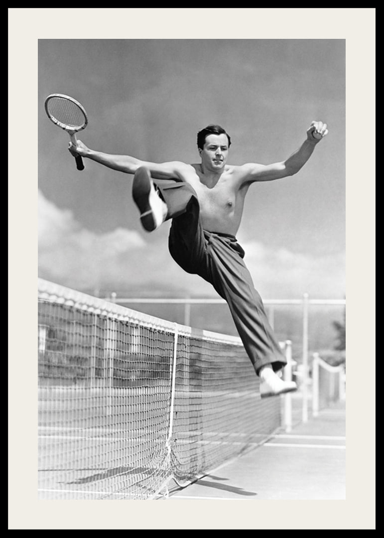 Black and white photo of bare-chested man jumping over tin netting-12