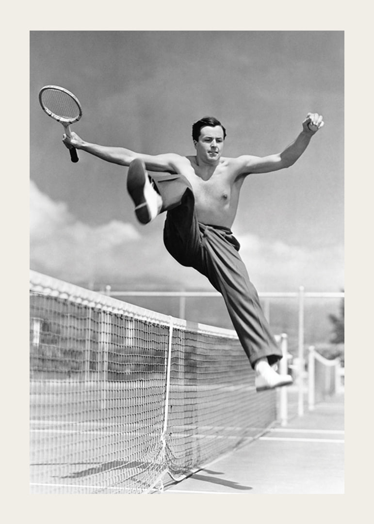 Black and white photo of bare-chested man jumping over tin netting-12