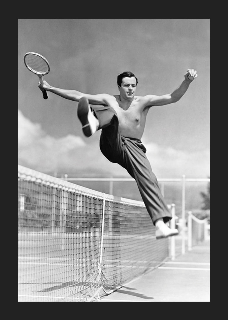 Black and white photo of bare-chested man jumping over tin netting-12