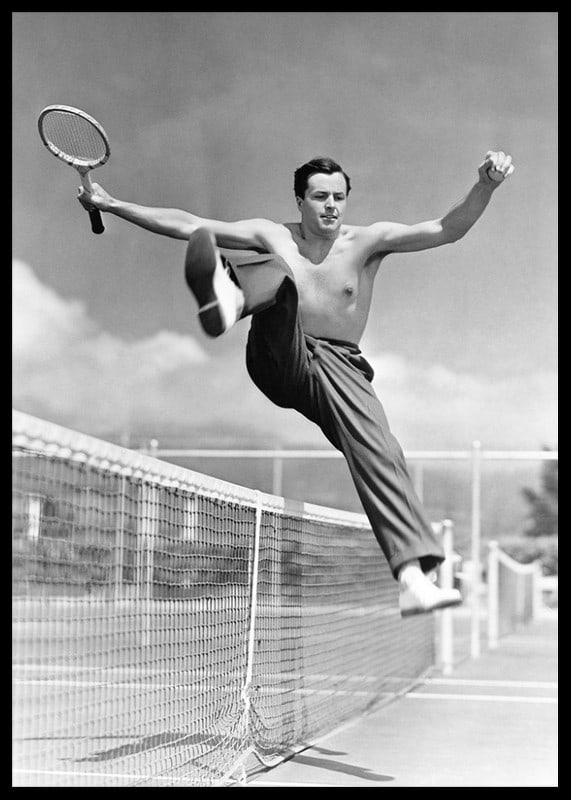 Black and white photo of bare-chested man jumping over tin netting-12