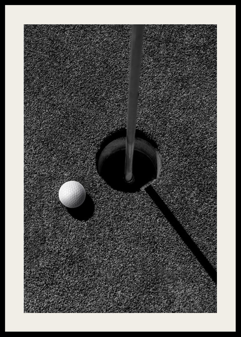 Black and white close-up of golf ball next to hole with flagpole-12