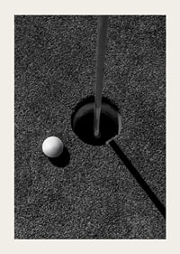 Black and white close-up of golf ball next to hole with flagpole-3