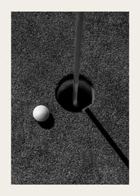 Primo piano in bianco e nero di una pallina da golf accanto alla buca con l'asta della bandiera-3