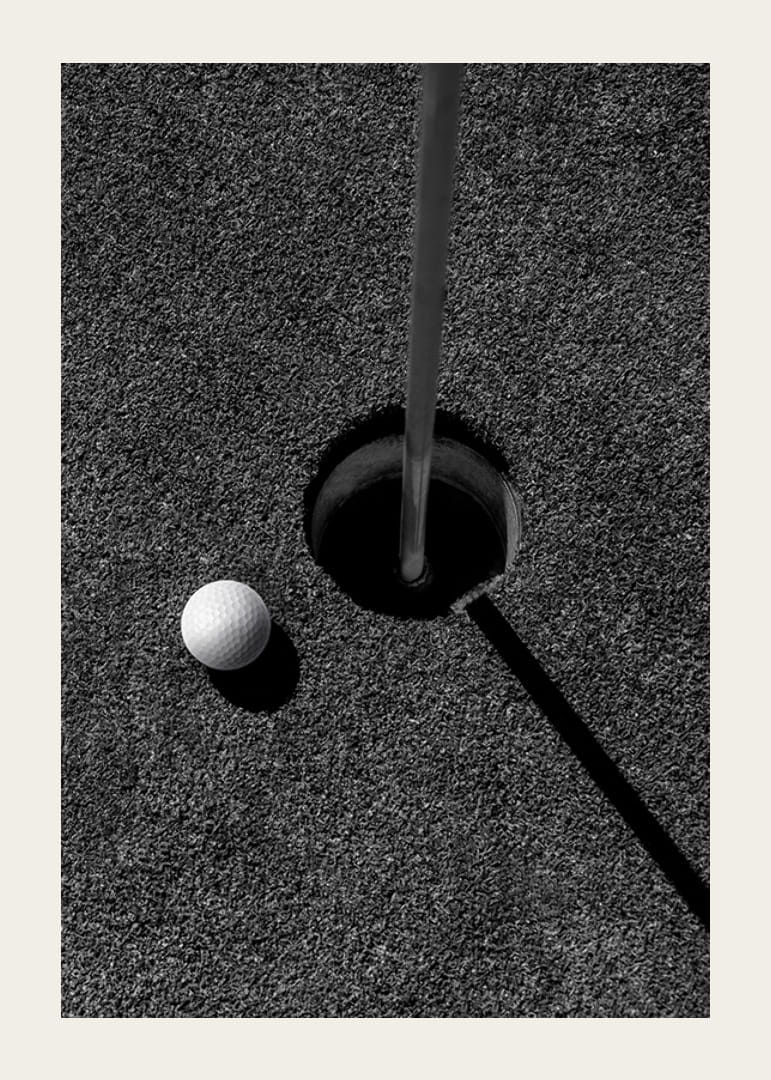 Primo piano in bianco e nero di una pallina da golf accanto alla buca con l'asta della bandiera-12