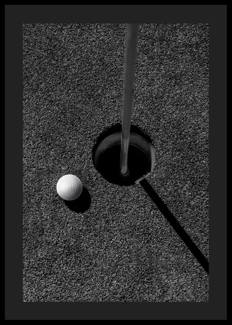 Primo piano in bianco e nero di una pallina da golf accanto alla buca con l'asta della bandiera-12