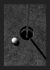 Black and white close-up of golf ball next to hole with flagpole-5