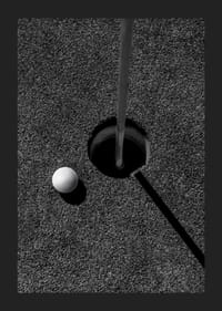 Primo piano in bianco e nero di una pallina da golf accanto alla buca con l'asta della bandiera-5