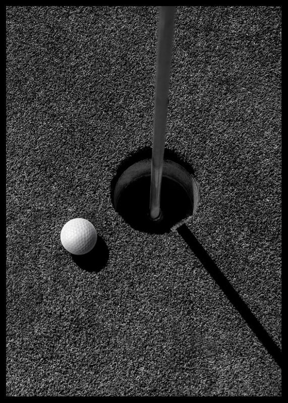 Black and white close-up of golf ball next to hole with flagpole-12