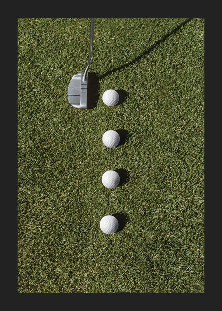 Golf club and four white golf balls on green lawn-12