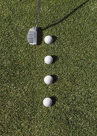 Golf club and four white golf balls on green lawn-7