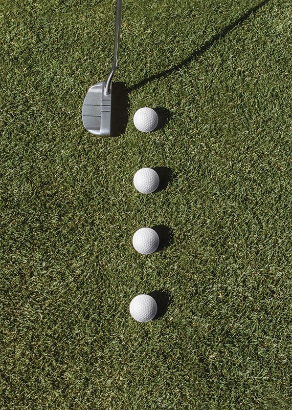 Golf club and four white golf balls on green lawn-12