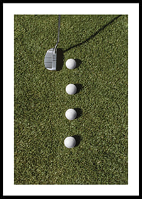 Golf club and four white golf balls on green lawn-0