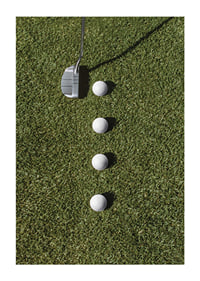 Golf club and four white golf balls on green lawn-1