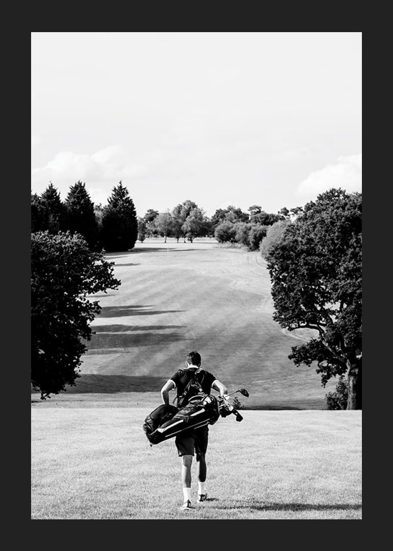 Golfer with bag against fairway in black and white landscape-12