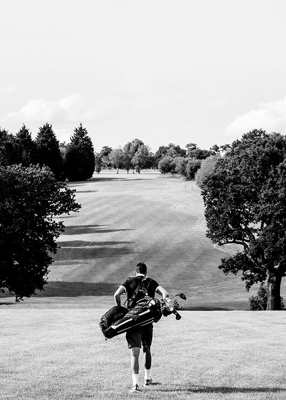 Golfer with bag against fairway in black and white landscape-12