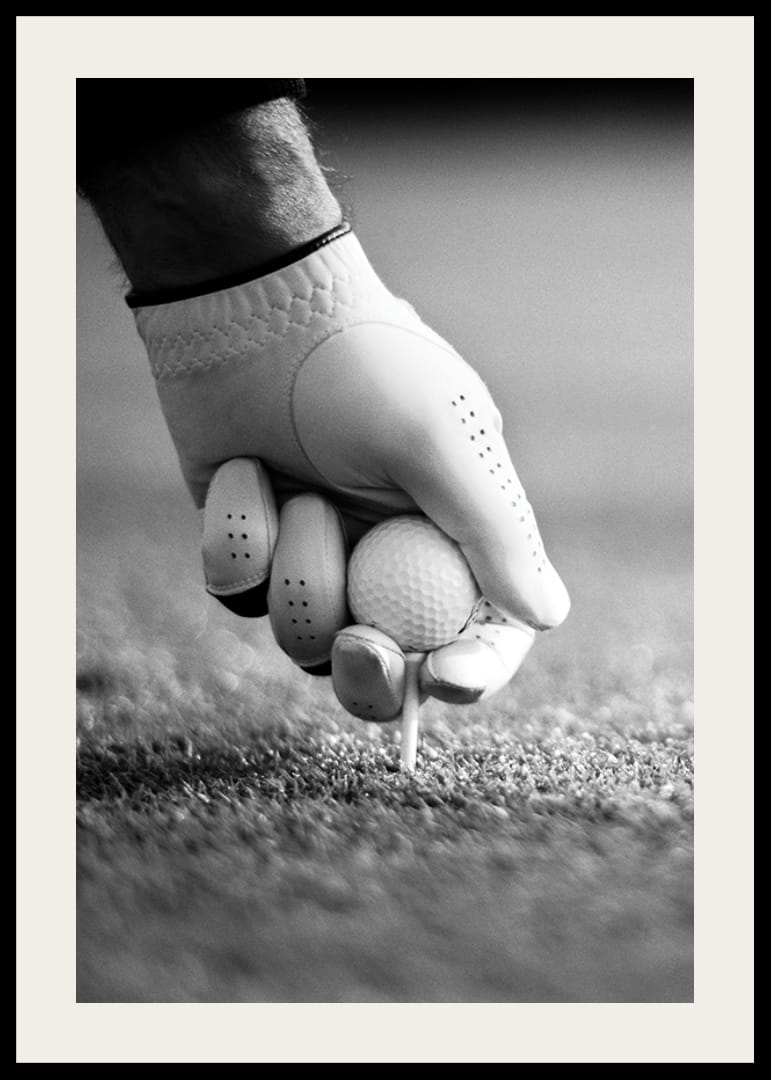 Svart-hvitt nærbilde av hånd med golfhanske som plasserer ballen på tee-12