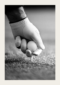Black and white close-up of hand with golf glove placing ball on tee-3