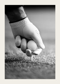 Svart-hvitt nærbilde av hånd med golfhanske som plasserer ballen på tee-3