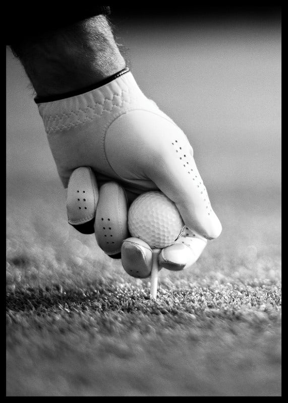 Black and white close-up of hand with golf glove placing ball on tee-12