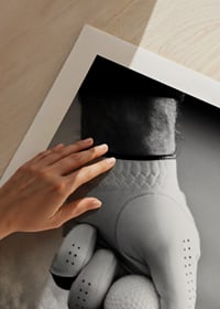 Black and white close-up of hand with golf glove placing ball on tee-9