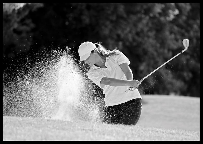 Black and white close-up of golfer in bunker shot, sand is smoking-12