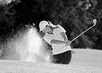 Black and white close-up of golfer in bunker shot, sand is smoking-7