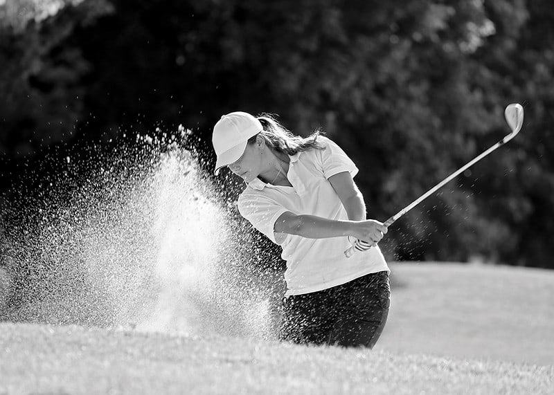 Black and white close-up of golfer in bunker shot, sand is smoking-12