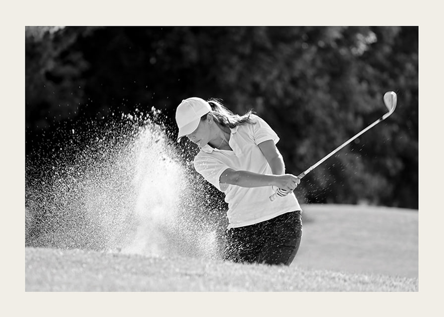 Black and white close-up of golfer in bunker shot, sand is smoking-12