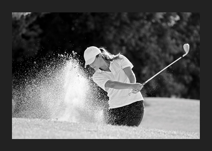 Black and white close-up of golfer in bunker shot, sand is smoking-12