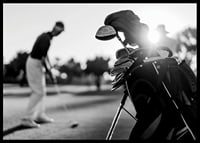 Svart-hvitt-bilde av golfbag i fokus, uskarp golfspiller bak-6