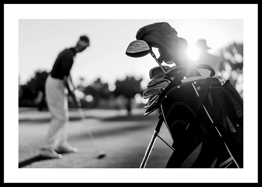 Svart-hvitt-bilde av golfbag i fokus, uskarp golfspiller bak-12
