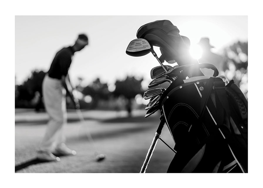Svart-hvitt-bilde av golfbag i fokus, uskarp golfspiller bak-12