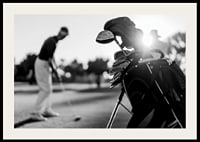Svart-hvitt-bilde av golfbag i fokus, uskarp golfspiller bak-2