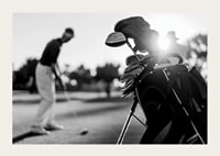 Svart-hvitt-bilde av golfbag i fokus, uskarp golfspiller bak-3