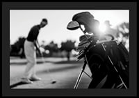 Svart-hvitt-bilde av golfbag i fokus, uskarp golfspiller bak-4