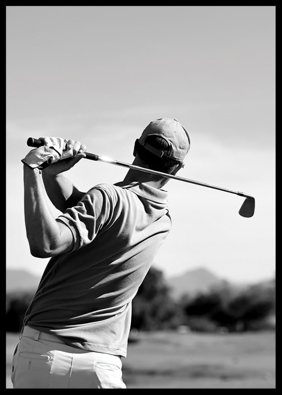 Black and white golfer swinging with club against bright sky-12