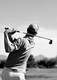 Black and white golfer swinging with club against bright sky-7